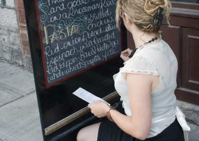 woman writing on sidewalk sign